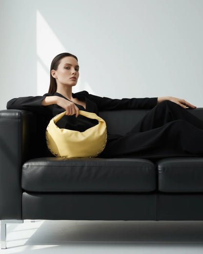 Designer bright yellow slouchy shoulder bag with a twisted top handle and silver metal studs along the edges | ALLBYB