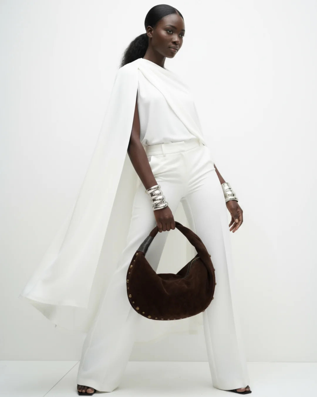 Designer brown slouchy shoulder bag with a twisted top handle and gold metal studs along the edges | ALLBYB