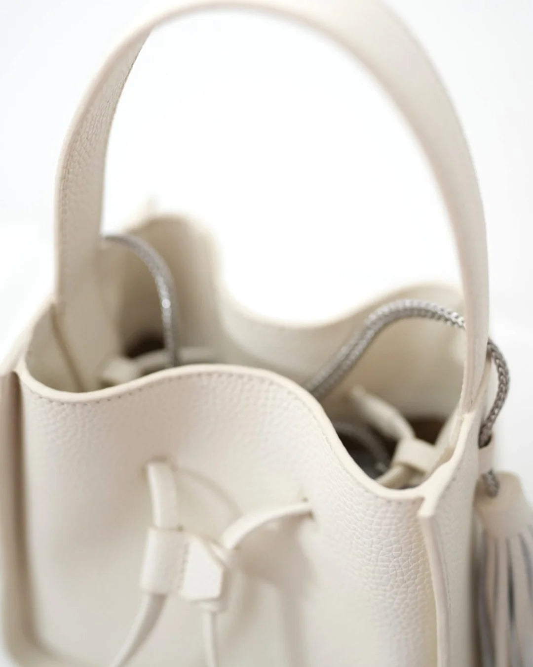 Designer beige leather bucket bag with a top handle and drawstring closure | ALLBYB