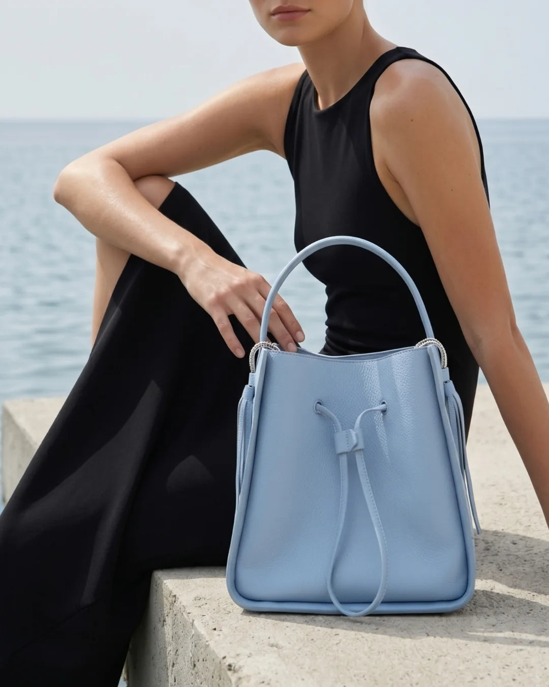 Designer light blue leather bucket bag with a top handle and drawstring closure | ALLBYB