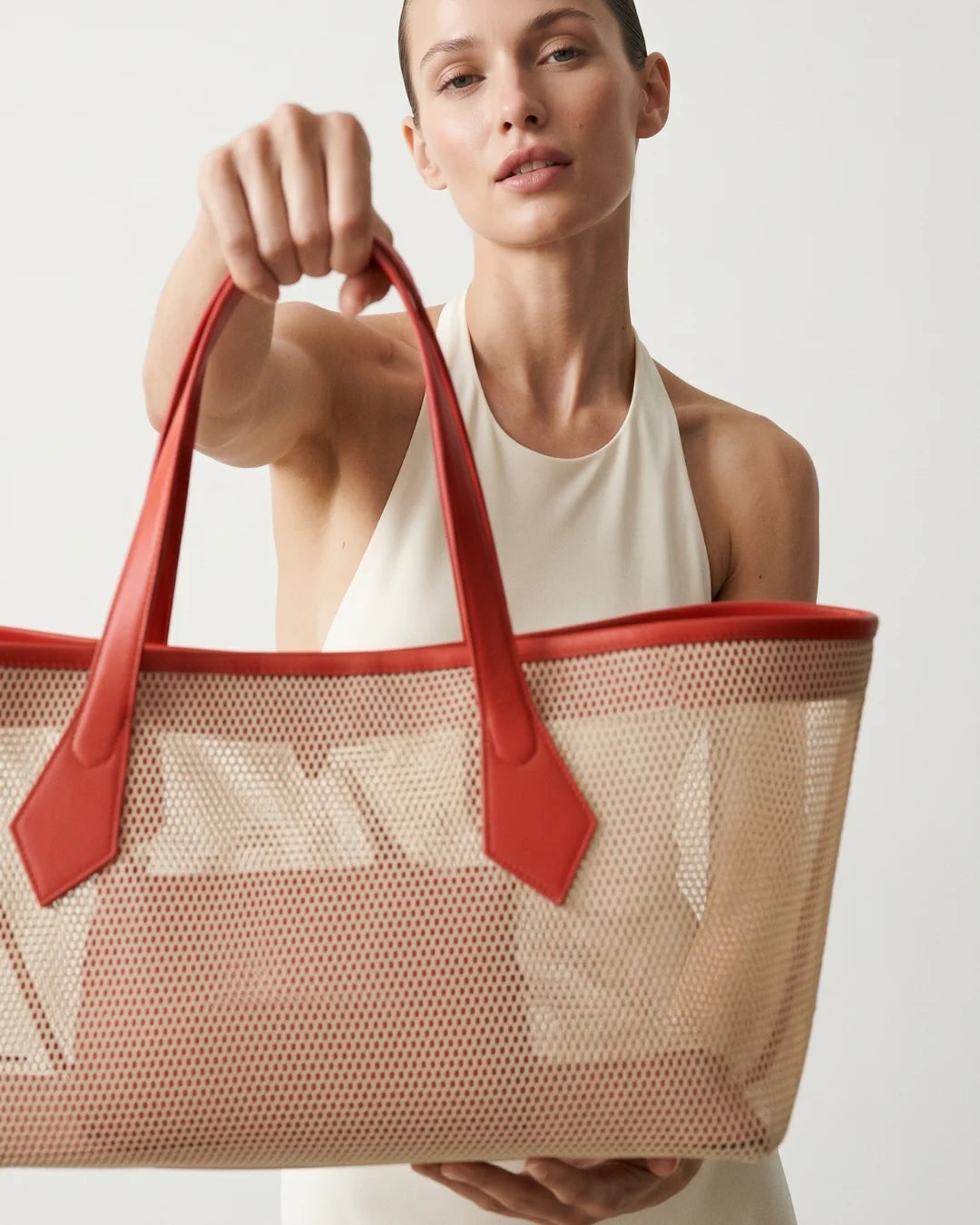 Structured designer mesh tote bag with a warm beige body and bright coral-red handles and trim | ALLBYB
