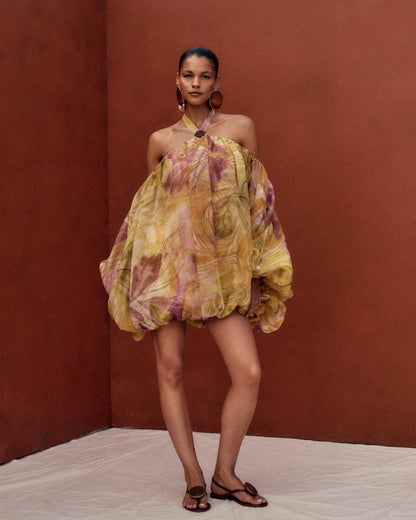 Woman wearing a colorful dress against a brown wall