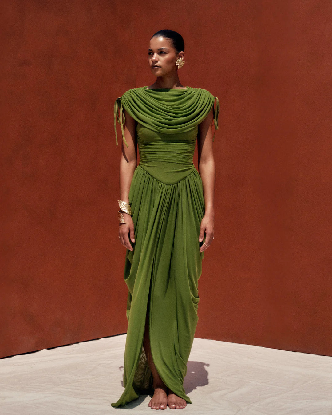 Woman wearing a green dress against a red-brown wall