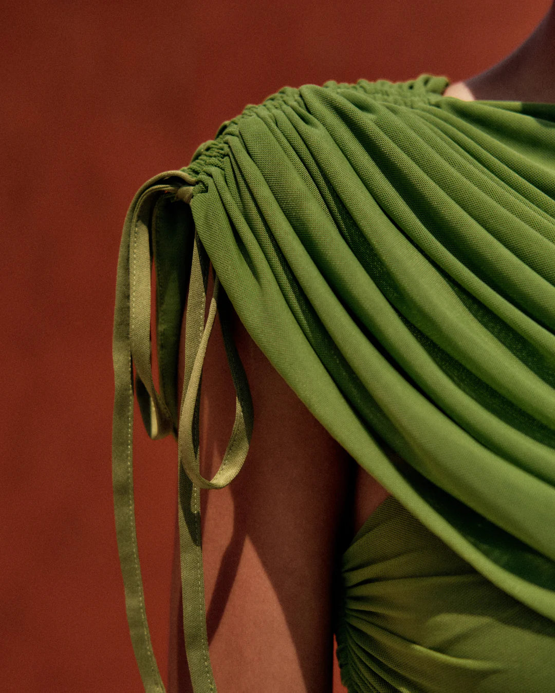 Green pleated garment with a strap on a red background