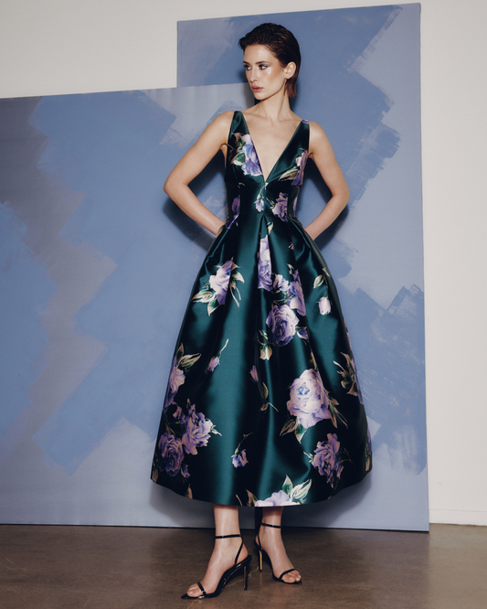 Woman wearing a dark green floral dress against a blue and gray abstract background