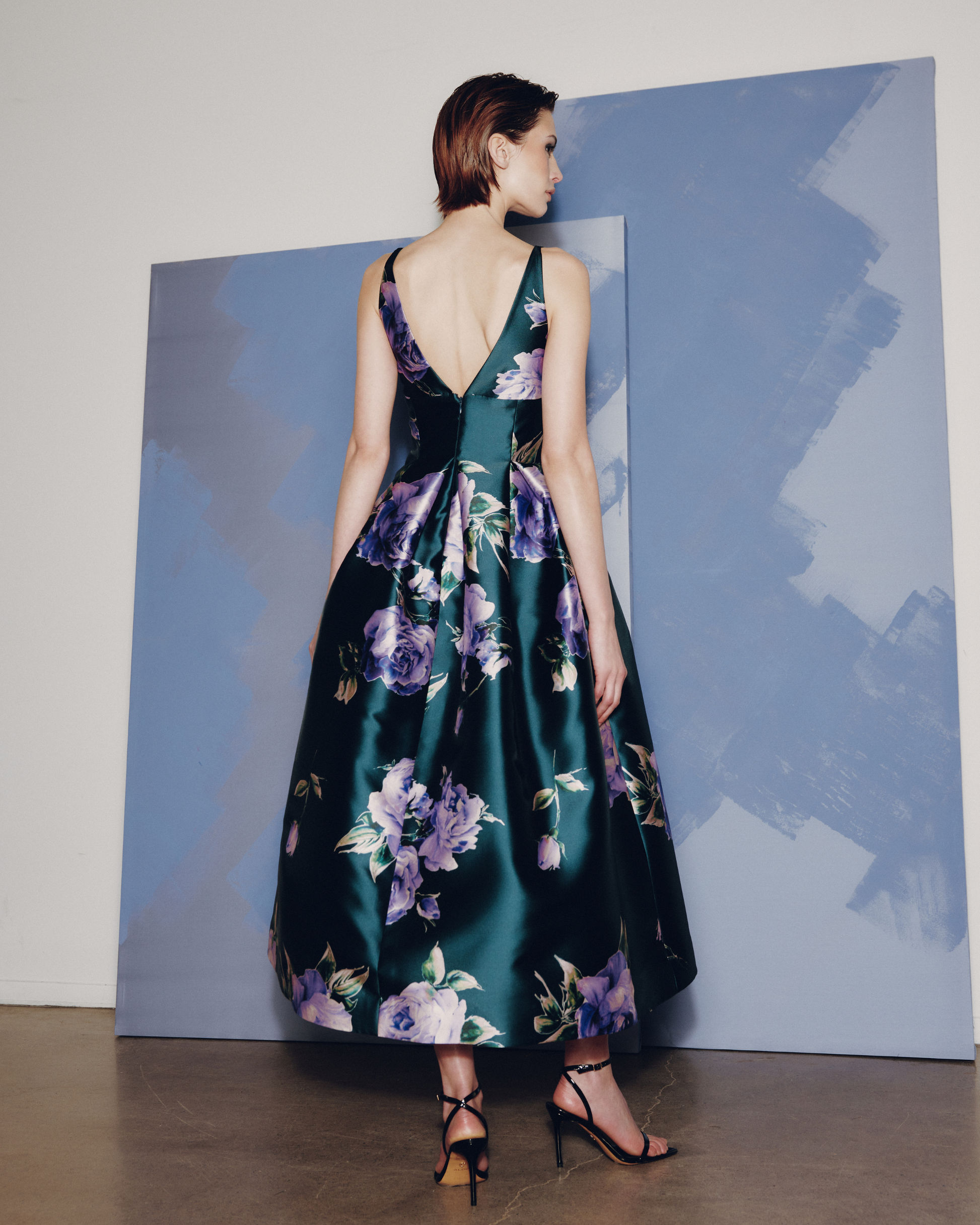 Woman wearing a floral dress standing against a plain background