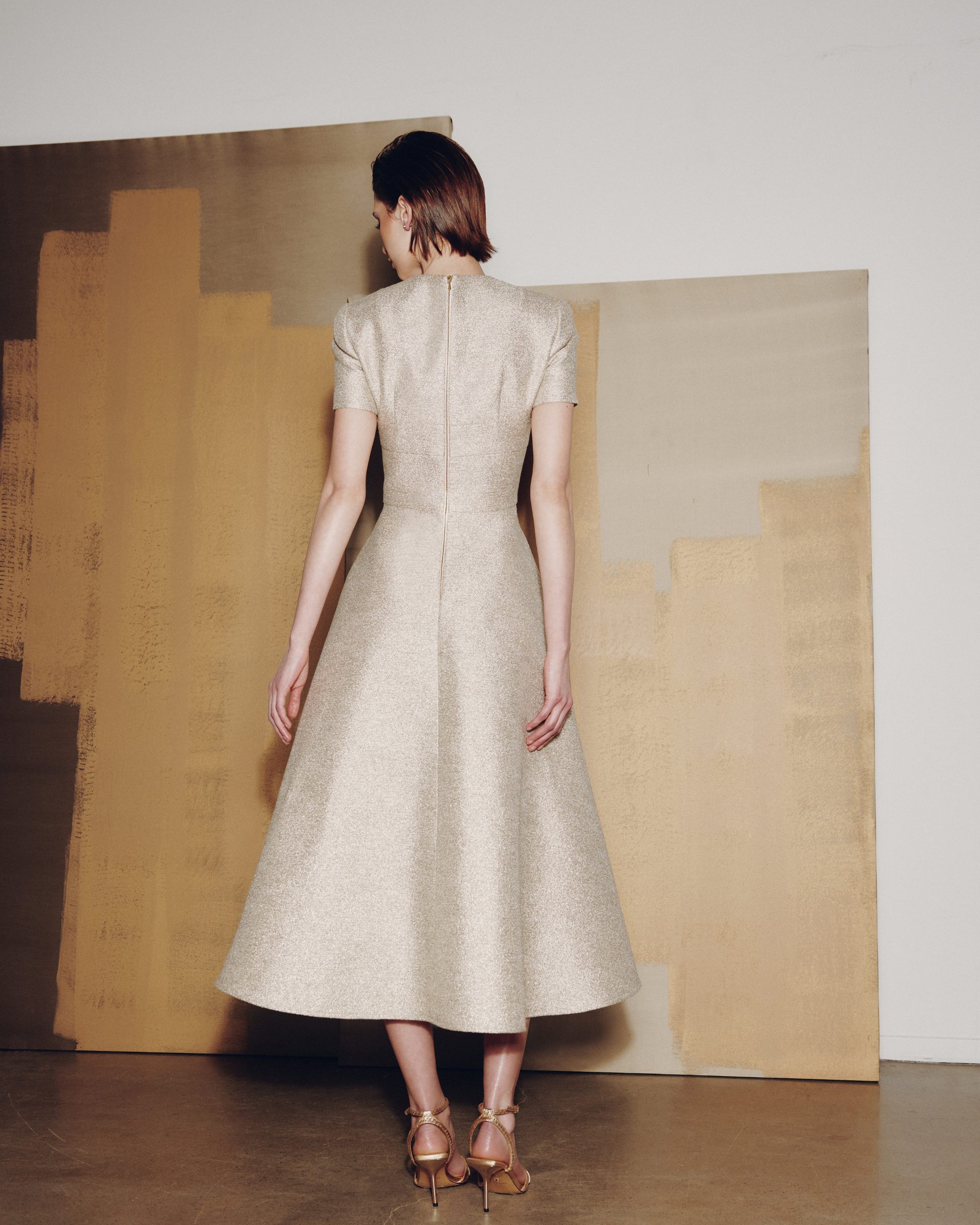 Woman in a beige dress standing in front of abstract art