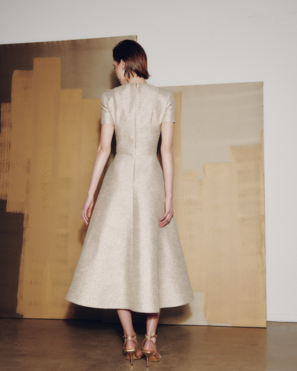 Woman in a beige dress standing in front of abstract art