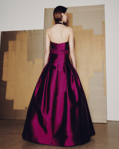 Woman in a burgundy evening gown standing in front of abstract art