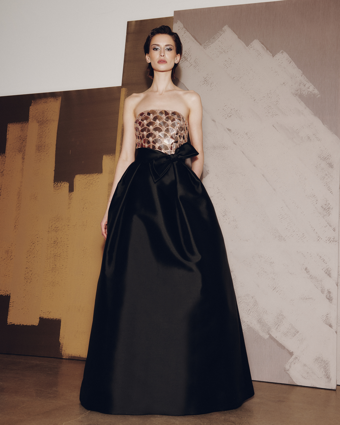 Woman wearing a strapless leopard print top with a black full skirt against an abstract painting background.