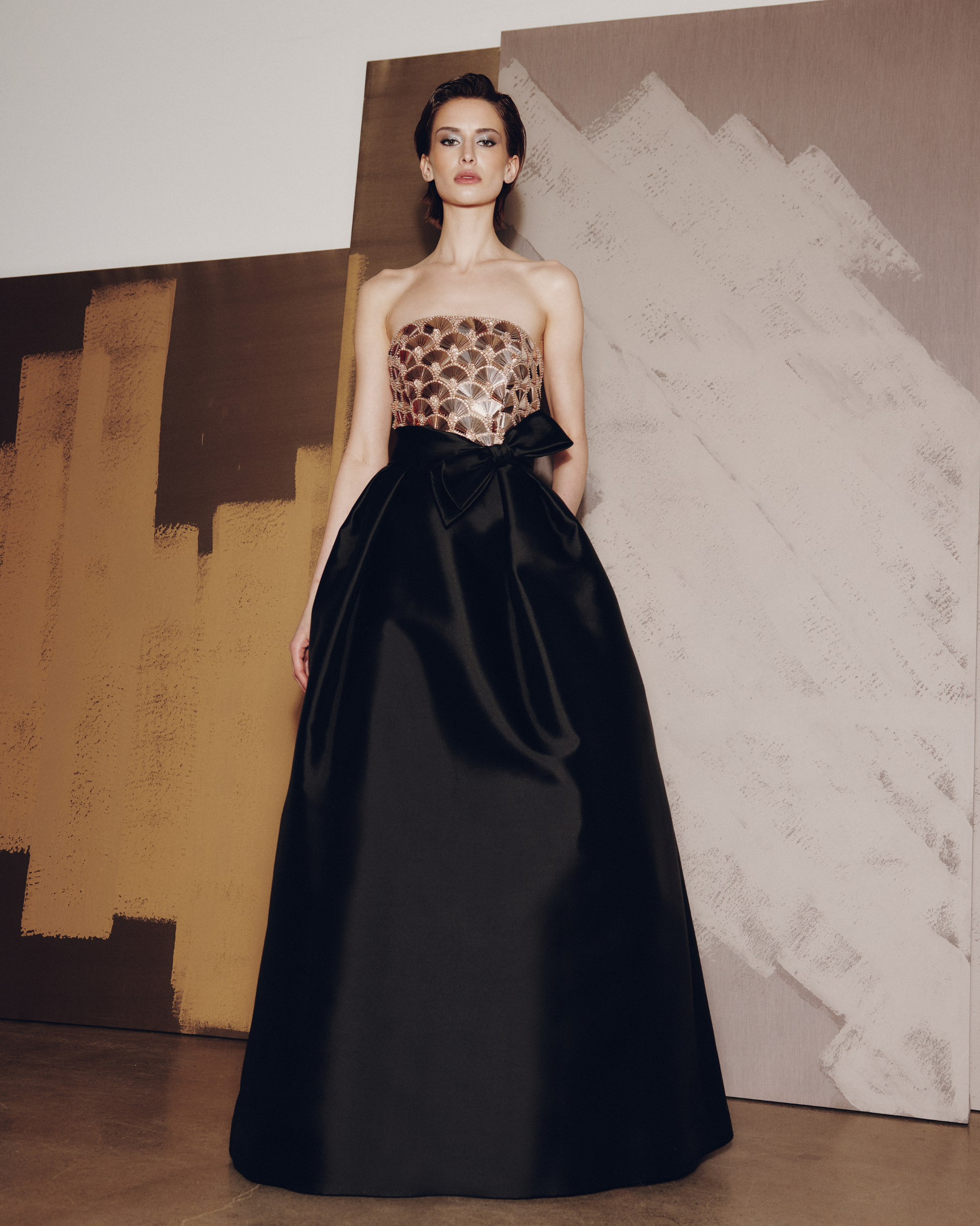 Woman wearing a strapless leopard print top with a black full skirt against an abstract painting background.