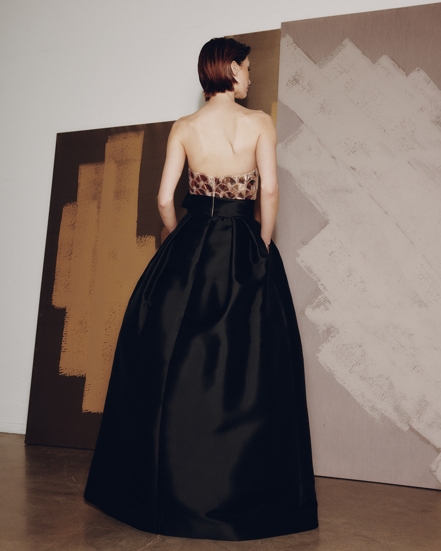 Woman in a black gown with a leopard print top standing in front of abstract art.