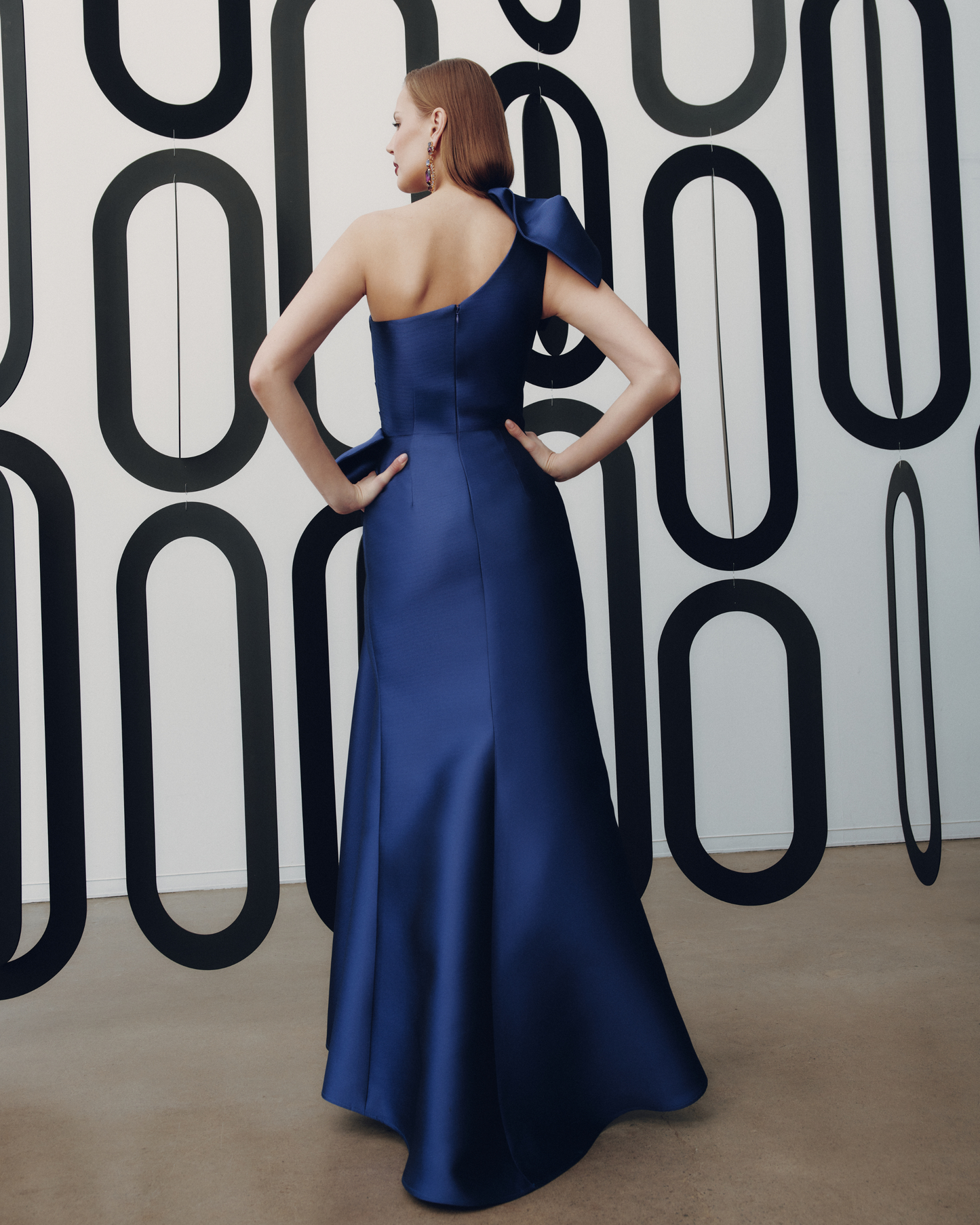 Woman in a blue evening gown against a patterned wall