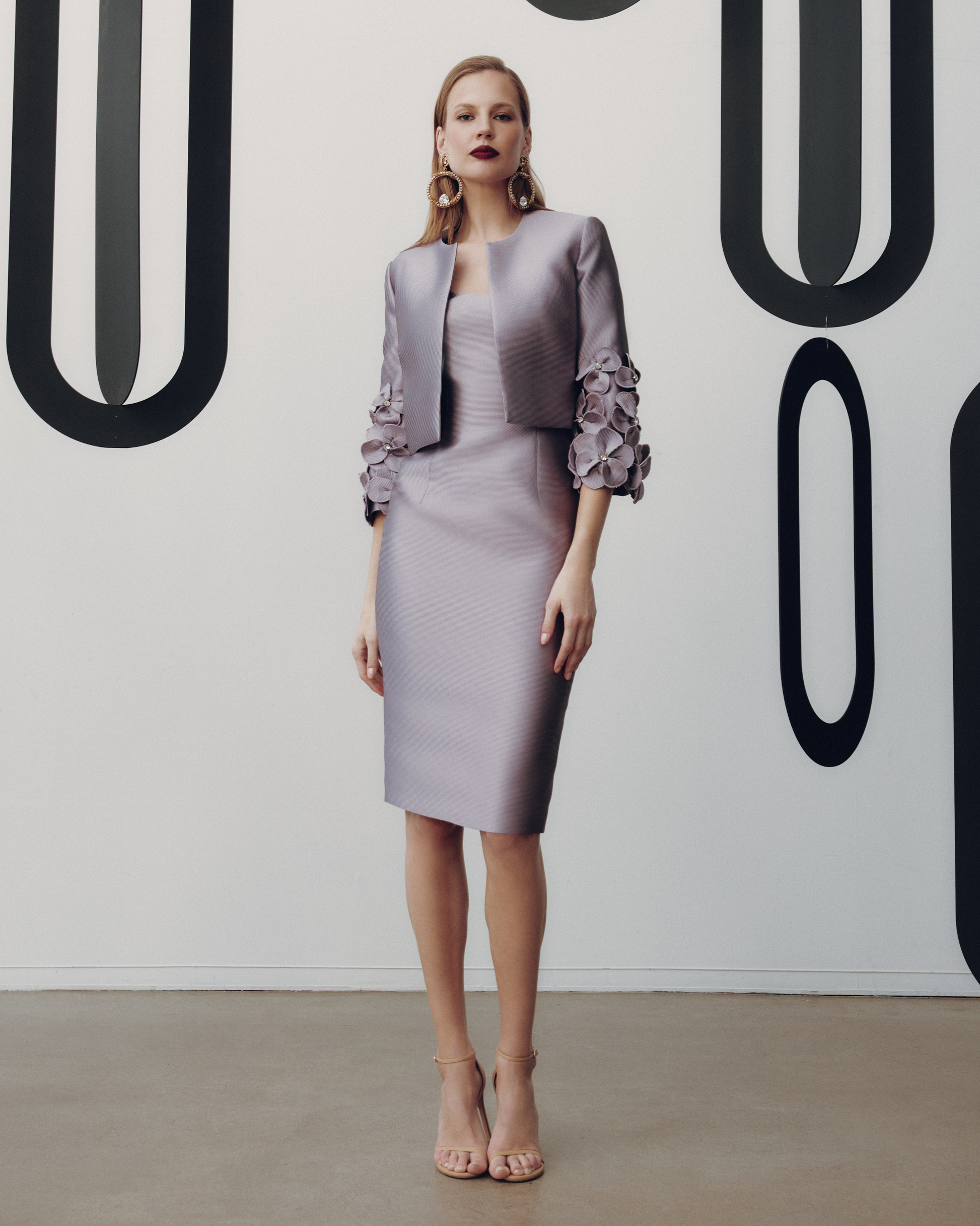 Woman wearing a gray dress with floral details against a minimalistic background