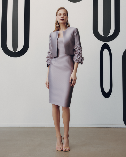 Woman wearing a gray dress with floral details against a minimalistic background