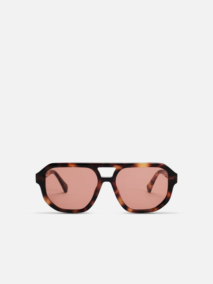 Sunglasses with tortoiseshell frame and pink lenses on a white background