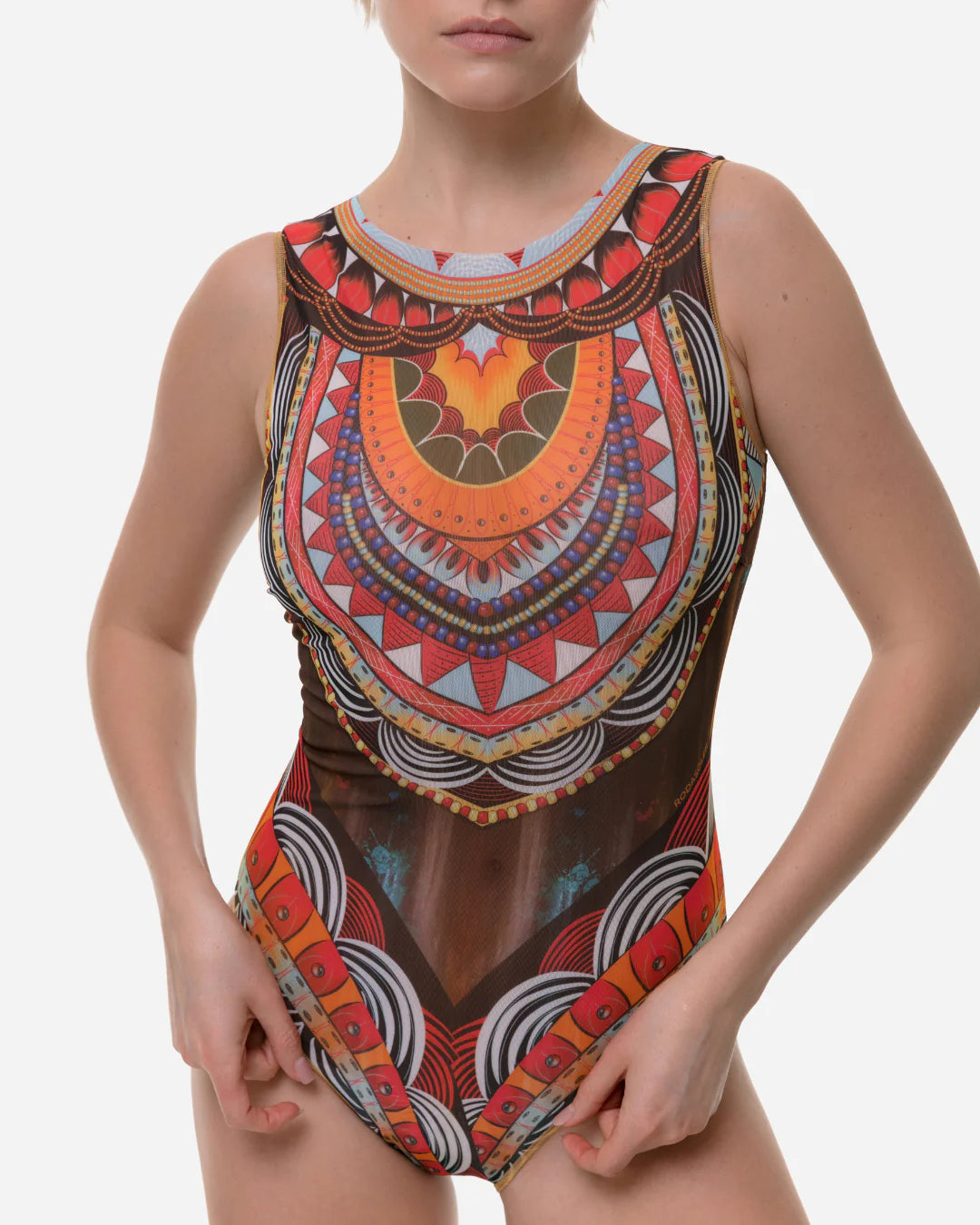 Designer sleeveless one-piece swimsuit with sheer mesh front and an intricate, colorful African dashiki-inspired geometric print in orange, red, yellow, brown, and white | RODA
