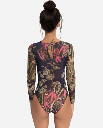 Designer long-sleeve one-piece swimsuit with a botanical jungle print on a sheer mesh fabric, featuring a dusty blue-gray base color with green, pink, and beige leaves | RODA