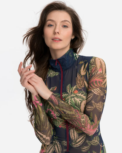 Designer long-sleeve swimsuit with a tropical leaf print in shades of green, pink, and beige over a dark gray base, featuring a dark navy mock neck collar and a dark red front zipper | RODA
