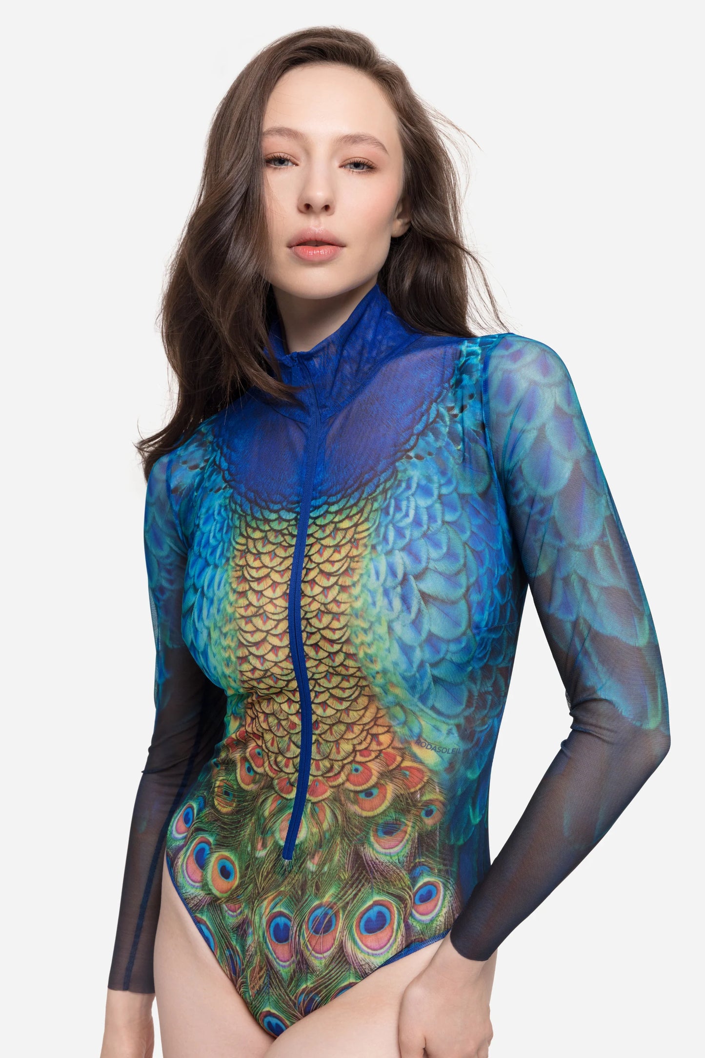 Designer long-sleeve swimsuit with a high collar and a front zipper, featuring a vibrant peacock feather and gold scale pattern in shades of blue, green, yellow, and orange | RODA